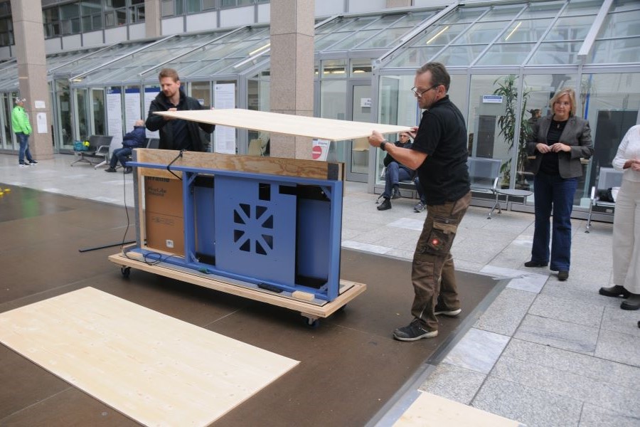 Zwei Männer öffnen eine Transportbox, in der sich das Medienterminal befindet.