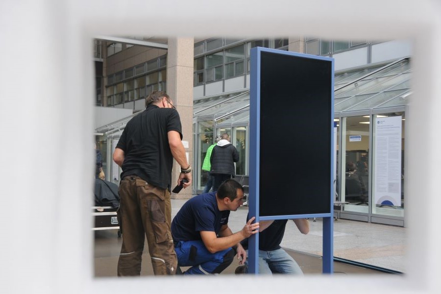 Drei Mitarbeiter installieren das Medienterminal.