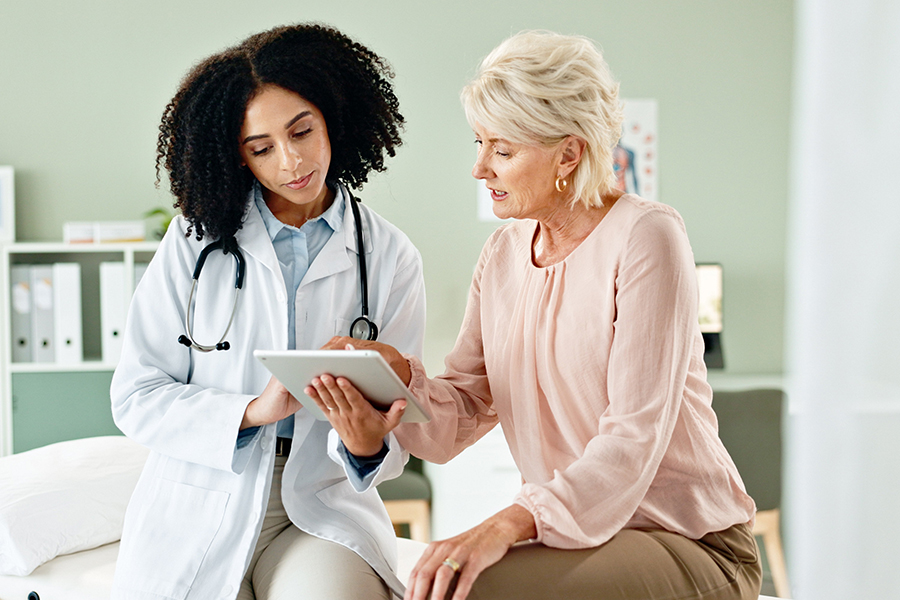 Weibliche medizinische Fachkraft erkl&auml;rt Patientin etwas anhand eines Tablets