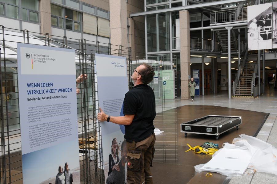 Ein Handwerker hängt eine Ausstellungstafel auf.