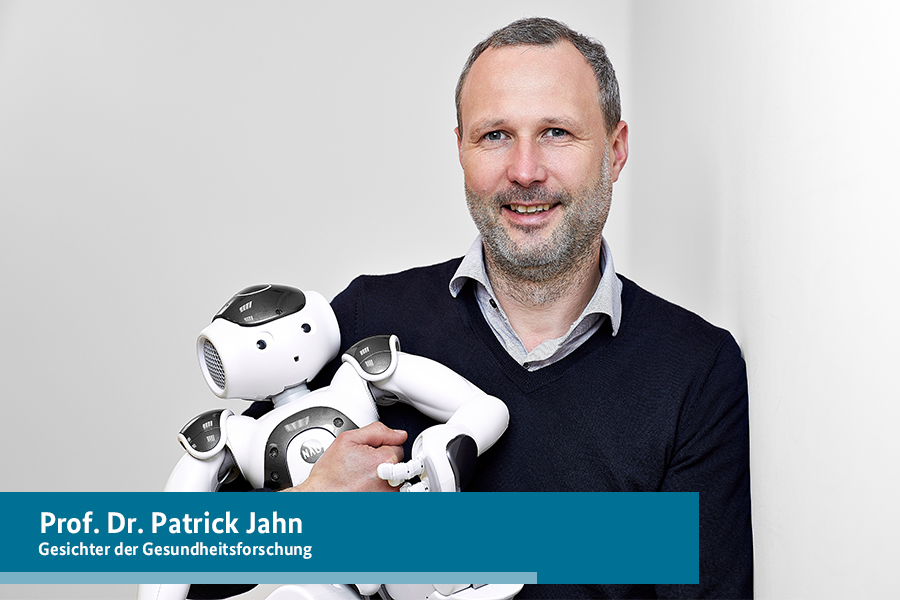Porträt von Prof. Dr. Patrick Jahn mit einem Roboter im Arm. Porträt von Prof. Dr. Patrick Jahn mit einem Roboter im Arm.