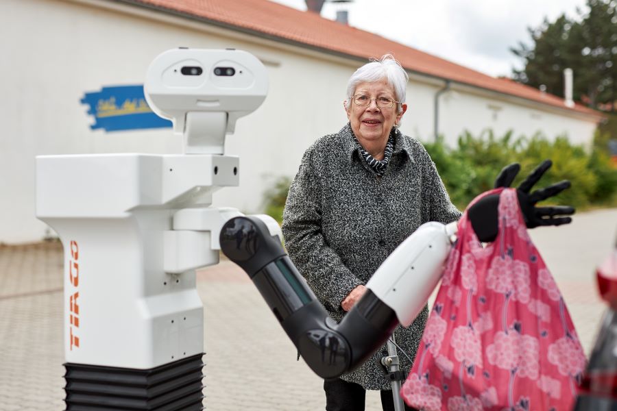 Ein Roboter trägt eine Einkaufstasche für eine ältere Dame. Ein Roboter trägt eine Einkaufstasche für eine ältere Dame.