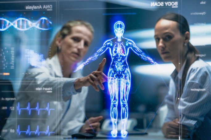 Zwei Ärztinnen schauen auf ein Hologramm eines menschlichen Körpers
