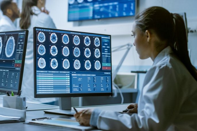 Eine Wissenschaftlerin schaut auf einen Monitor mit Gehirn Scans.