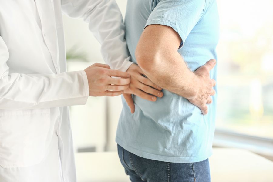 Ein Arzt klopft die Nierenregion eines Patienten bei einer Untersuchung ab. Ein Arzt klopft die Nierenregion eines Patienten bei einer Untersuchung ab.