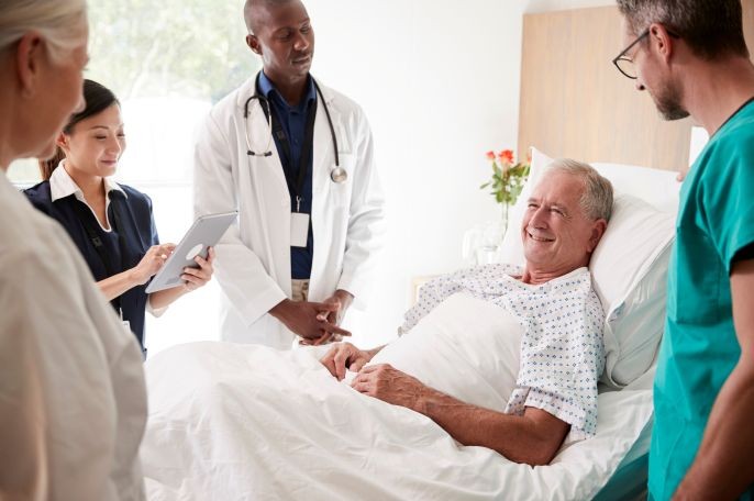 Vier Ärztinnen und Ärzte stehen bei einem Patienten am Bett.