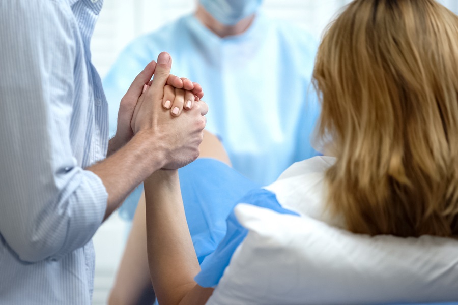 Mann hält Hand seiner Partnerin beim Geburtsvorgang