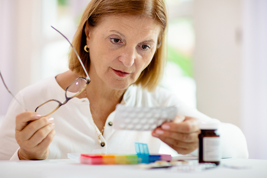 Eine ältere Patientin betrachtet ihre Tabletten. Eine ältere Patientin betrachtet ihre Tabletten.