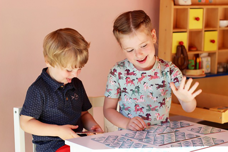 Mädchen und Junge sitzen im Kindergarten nebeneinander am Tisch