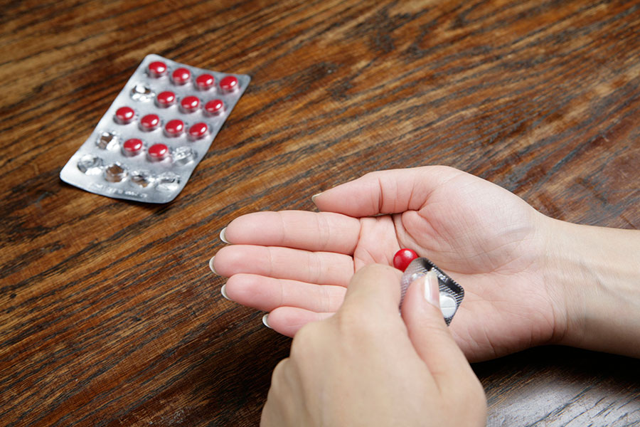 Eine Frau drückt eine Tablette aus der Verpackung.
