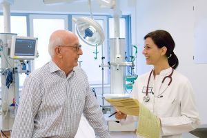 Eine &Auml;rztin spricht mit einem Patienten in einem Operationsraum.