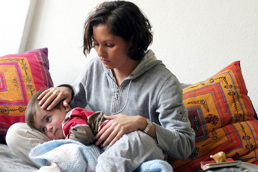 Mutter hält erschöpftes Kind auf dem Schoß.