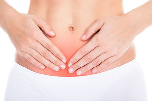 Eine Frau legt beide Hände auf den schmerzenden Bauch.