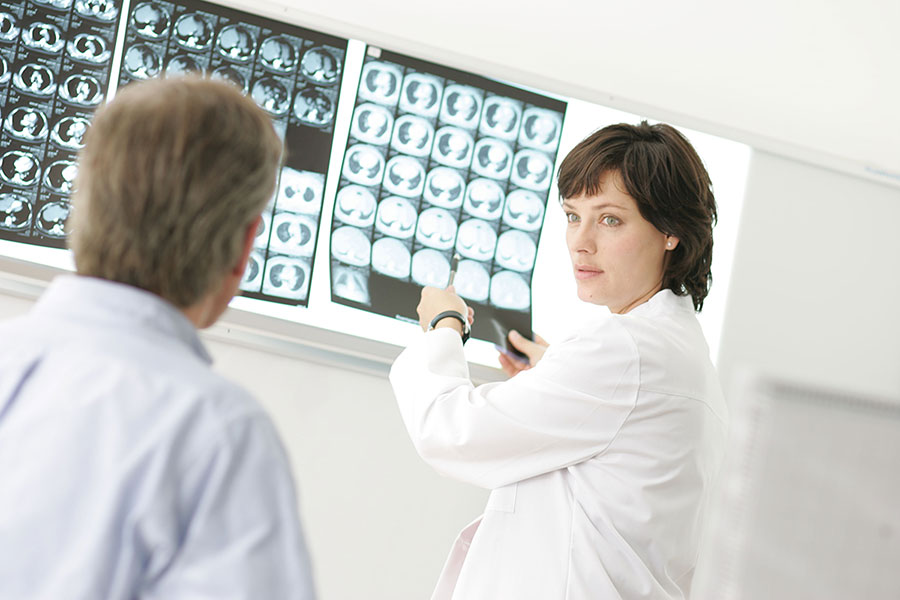 Ärztin schaut mit Patient Computertomograph-Bilder an.