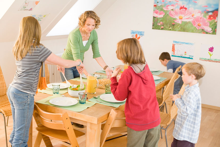 Eine Mutter und ihre Kinder decken einen Tisch Eine Mutter und ihre Kinder decken einen Tisch