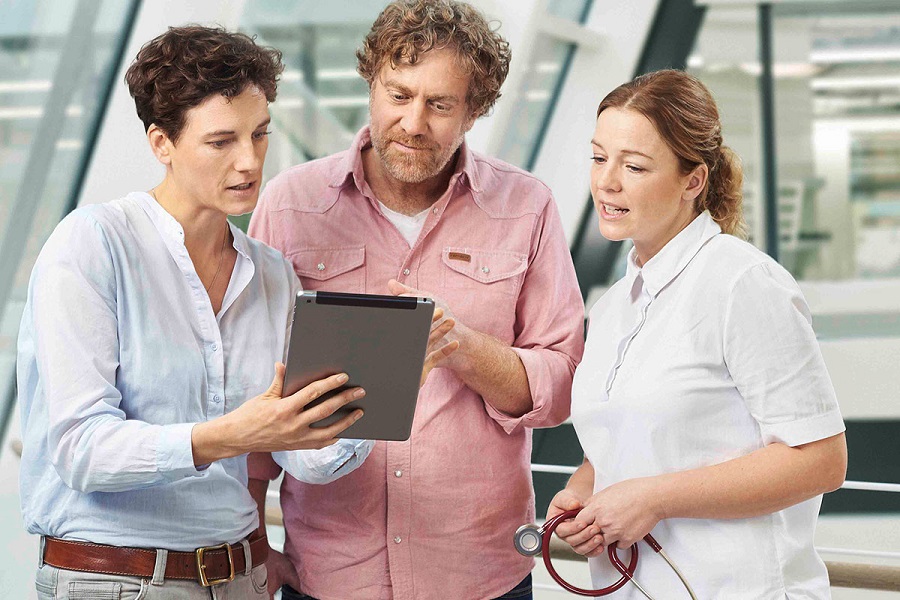 Wissenschaftlerin, Patient und Ärztin stehen zusammen