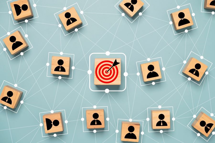 Schematische Darstellung von miteinander quervernetzten Personen mit einem zentralen Ziel, dargestellt durch eine rote Zielscheibe in der Mitte des Bildes.