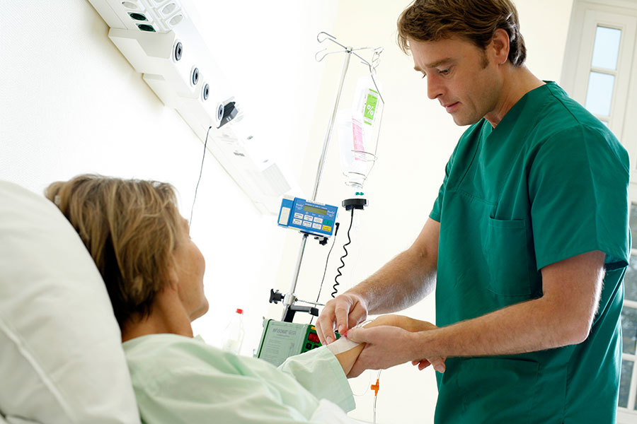 Ein Pfleger versorgt eine Patientin im Krankenhaus.