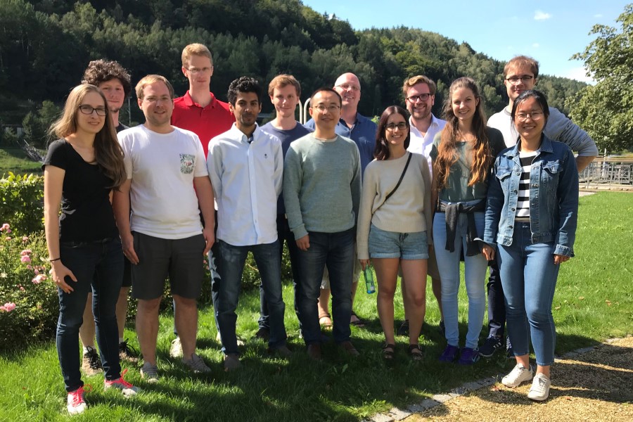 Gruppenbild von 13 Forschenden, die auf einer Wiese stehen. 