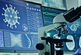 Ein Miskroskop vor zwei Bildschirmen