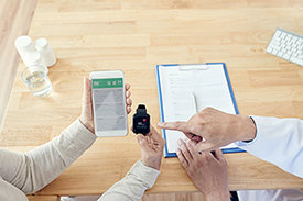 Ältere Patientin zeigt mobile Anwendung von Gesundheitsdaten wie Herzfrequenz