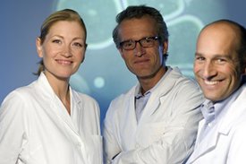 eine Ärztin und zwei Ärzte lächeln in die Kamera