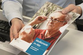 Eine Person hält die Broschüre Medikamente im Alter in den Händen