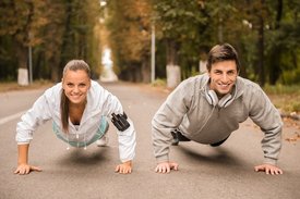 Eine Frau und ein Mann machen auf einer Straße Liegestütze