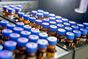 Im Labor: Viele kleine braune Fläschchen mit blauen Deckeln stehen in einer Haltevorrichtung