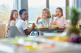 Fröhliche Kinder am Frühstücktisch Melone essend