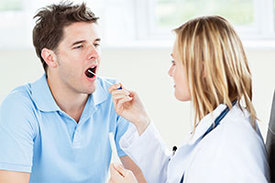 Ärztin entnimmt einem Patienten Speichelprobe mit einem Wattestäbchen.