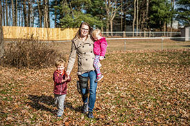Mutter mit Orthese geht mit zwei Kindern spazieren.
