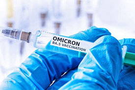 Hand hält Impfspritze mit Omicron-Impfstoff