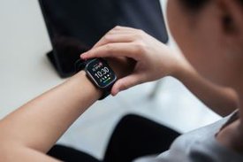 Junge Person kontrolliert verschiedene Gesundheitsparameter auf einer Smartwatch.
