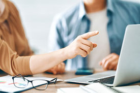 Zwei Personen sitzen am Computer und diskutieren miteinander
