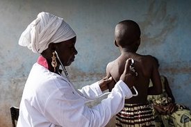 Eine Ärztin horcht den Rücken eines Kindes ab