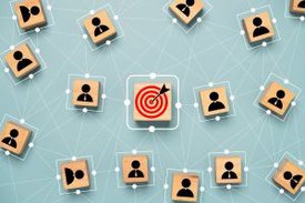 Schematische Darstellung von miteinander quervernetzten Personen mit einem zentralen Ziel, dargestellt durch eine rote Zielscheibe in der Mitte des Bildes.