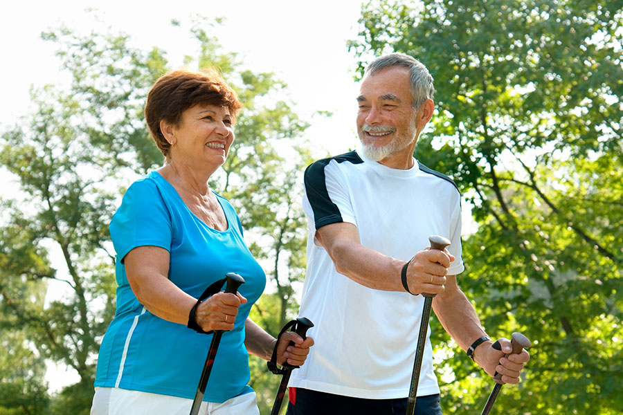 Lachendes älteres Paar beim Nordic Walking