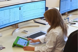 Eine Ärztin sitzt an einem Schreibtisch vor mehreren Monitoren und einem Tablet.