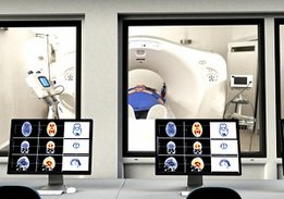 Zwei Computerbildschirme vor einem MRT-Gerät mit Patientin